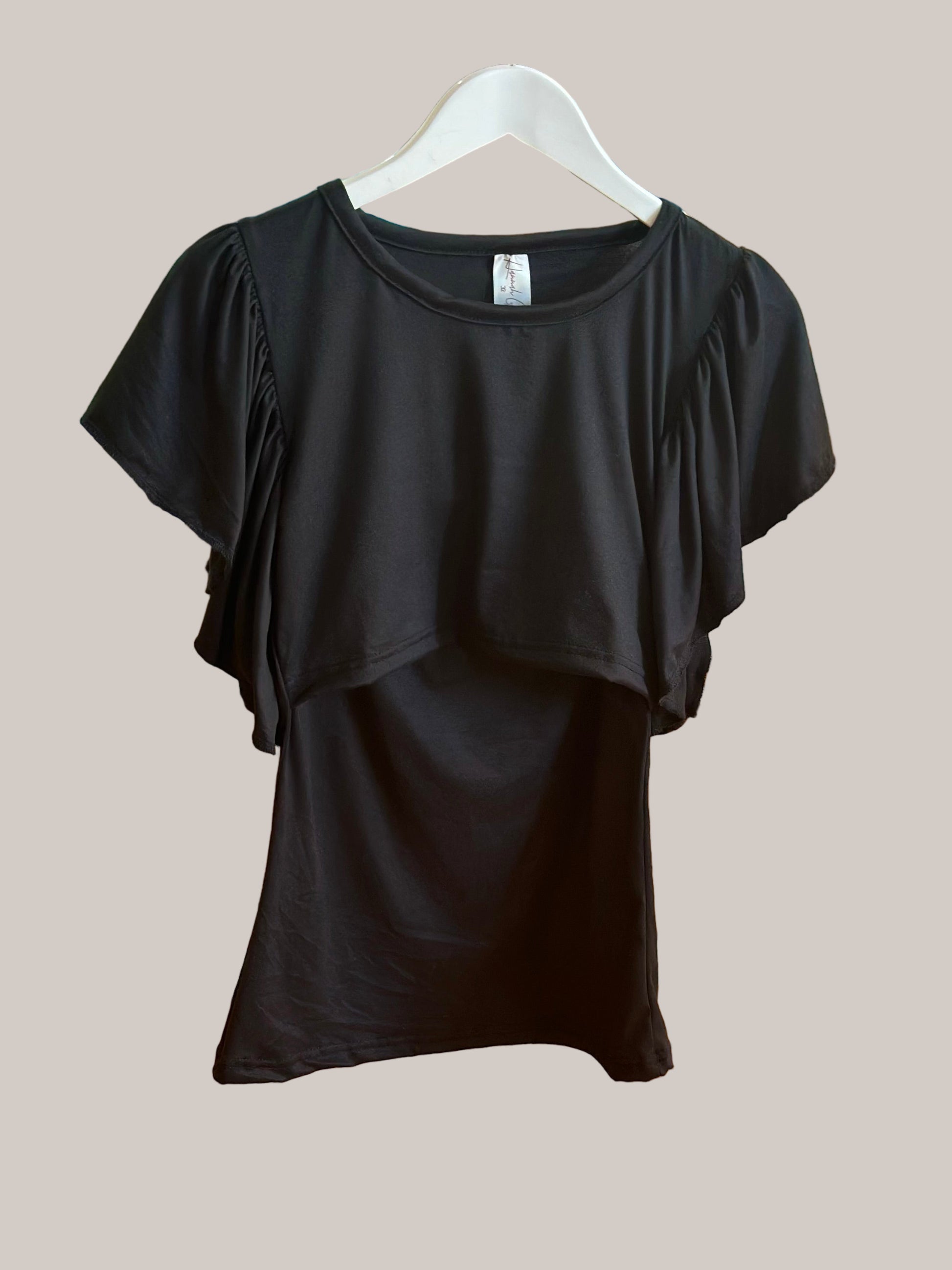 Black top on a hanger against a wooden floor background