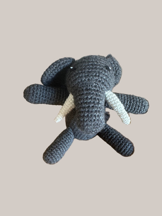 Hand-crocheted gray elephant toy on a beige background